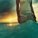 Woman in the waves with a golden horizon