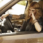 fashion shoot photo of a blonde woman dressed as a hippie at the wheel of a brown car