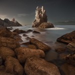 night photograph of a rocky outcrop on a coastline
