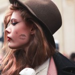 portrait of model frida gustavsson wearing a hat with lipstick mark on cheek