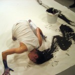 photograph of performance art of a woman painting with her hair