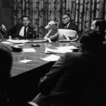 black & white photo of a dog sitting in on a conference