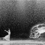 black & white photo of a ballet dancer on a stage filled with water, rain and rocks
