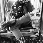 Stanley Kubrick looking bored holding a film camera
