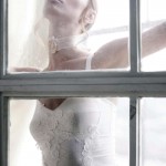 woman in white dress and veil with face against window
