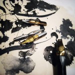 ink pens and nibs on paper with ink scrawls and stains