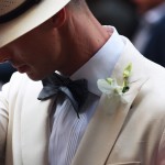 man in linen suit adjusting hat
