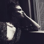 Rosie Huntington-Whiteley in a stark black & white photo staring out of a window grille