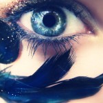 close up of woman's blue eye with raven's feather