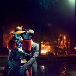 man in suit and sunglasses fondling woman in hat in park at night