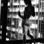 kate moss standing against skyscraper window