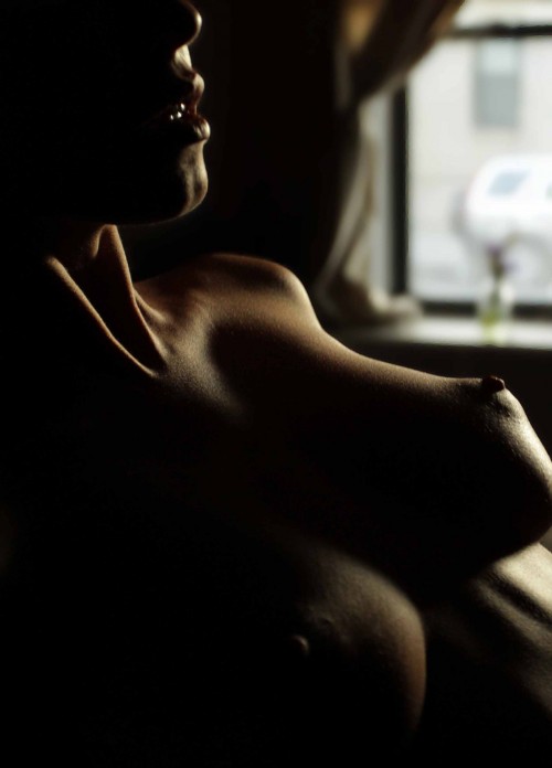 nude woman reclining in seat near window