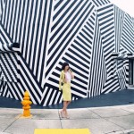 woman in yellow suit in front of stripey building