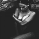 nude woman submerged in water near rocks
