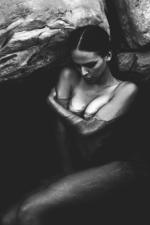 nude woman submerged in water near rocks