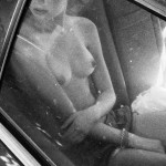 nude woman in car looking out window