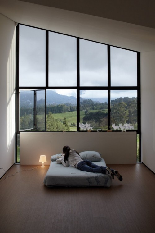 photograph of a woman on a bed before a large window looking onto a mountain vista