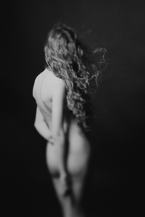 black & white shot of the rear of a nude woman with flowing hair