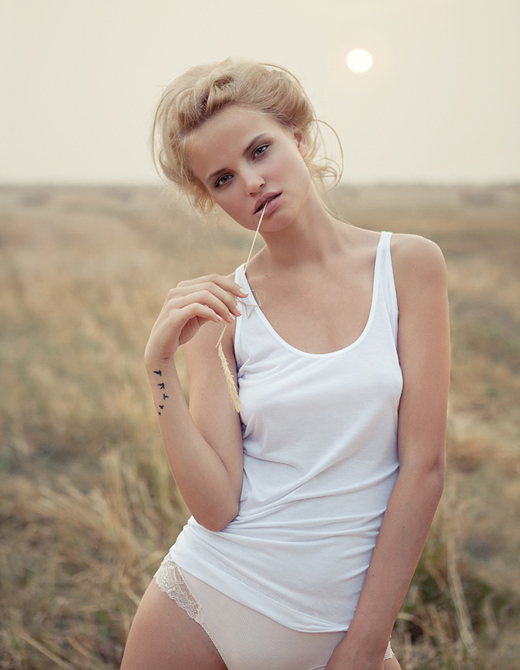 Woman in a field at dawn in a white tank top