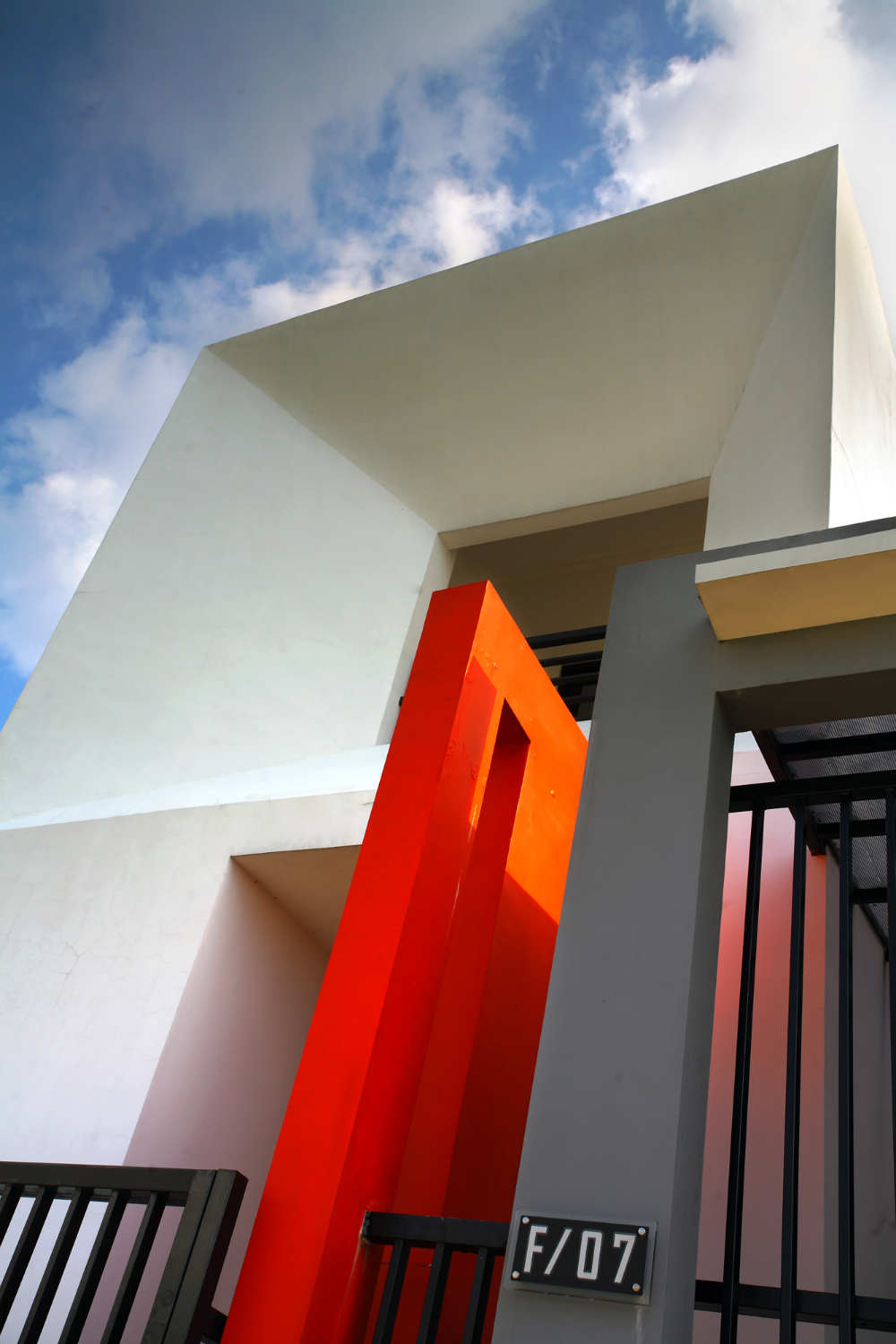 side of a white and grey building with a bright orange architectural feature