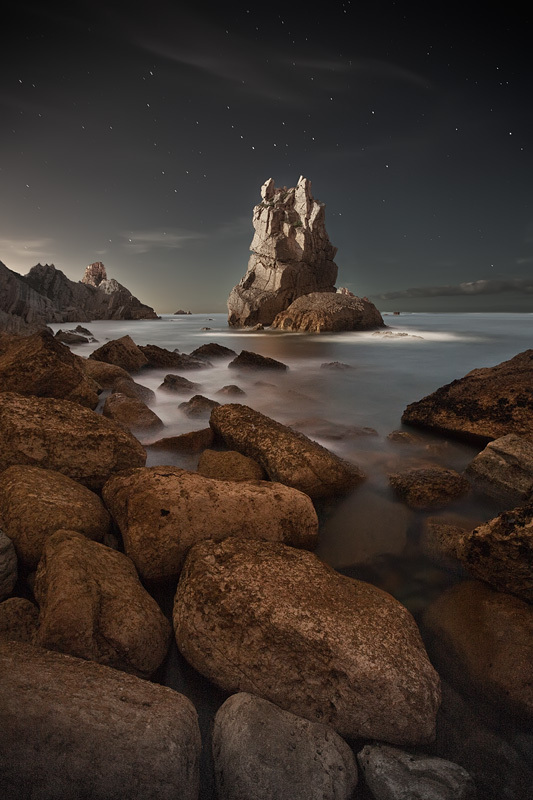 night photograph of a rocky outcrop on a coastline