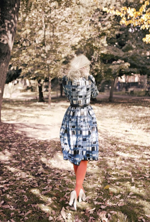 photo of a woman in a blue dress with red stockings walking amongst trees
