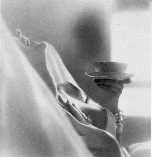 Black and white picture of a laughing nude woman holding a teacup