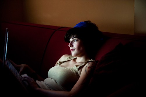 picture of a woman sitting on a couch looking at a computer screen