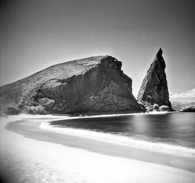 black & white photo of two rocky outcrops near a beach