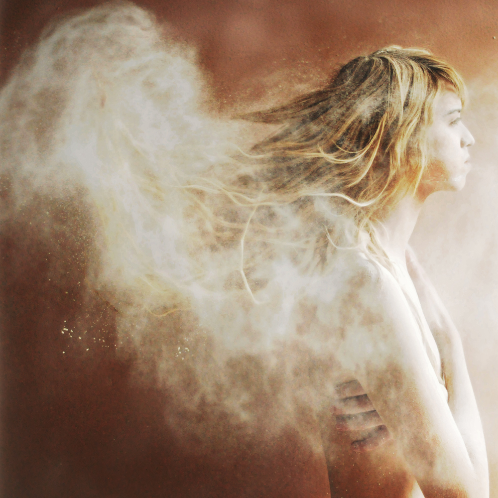photograph of a nude woman with a dust cloud