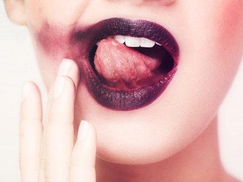 Woman with smeared lipstick licking her teeth