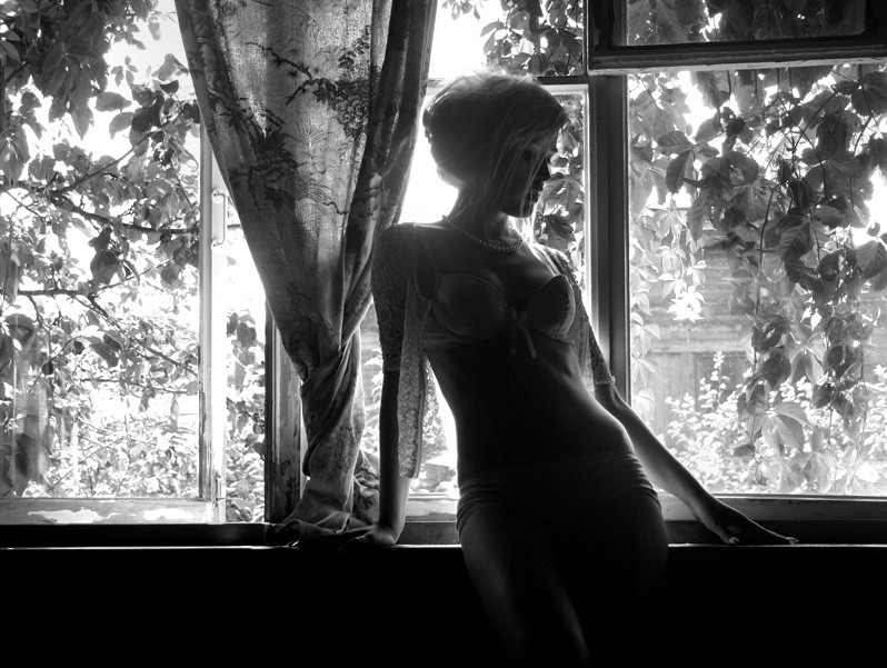 black & white photo of model against window