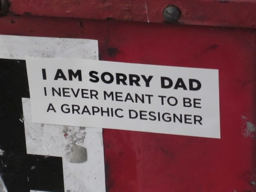 humorous sign about designers on the back of a vehicle
