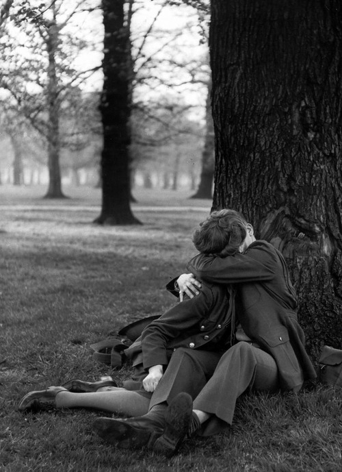 black & white photo of a man kissing a woman under a tree