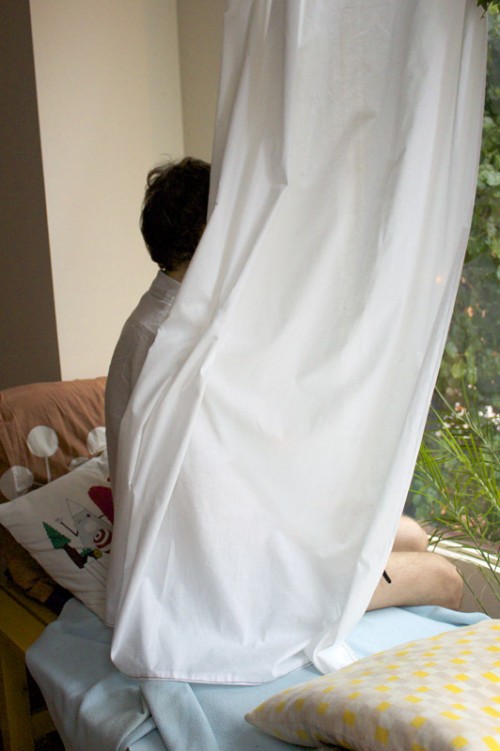 woman near window obscured by white curtain