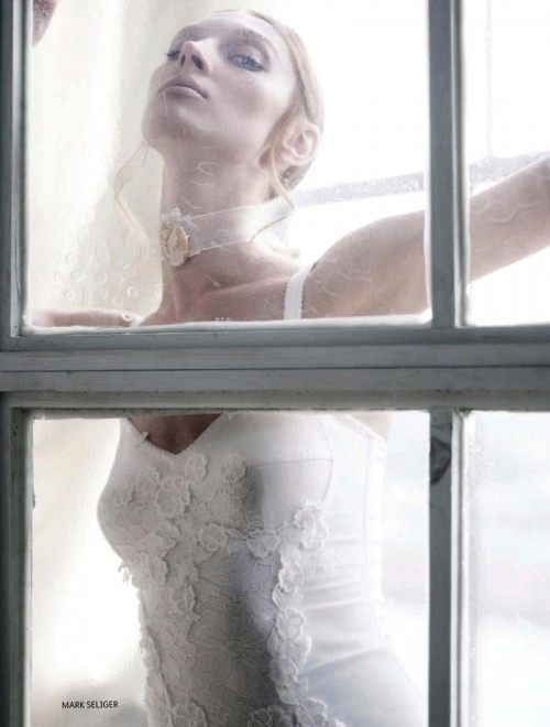 woman in white dress and veil with face against window