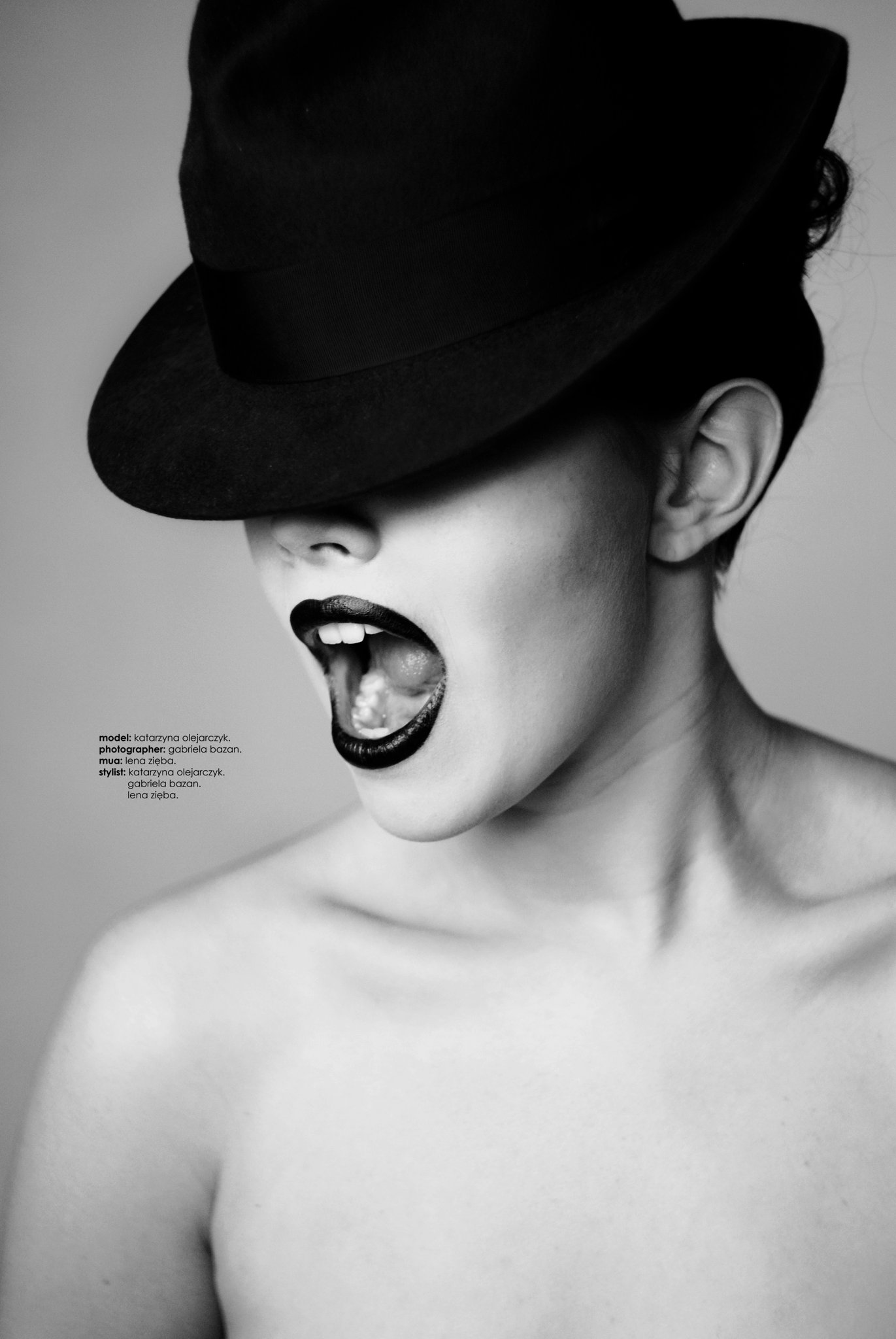 Model with mouth open in a cry and eyes covered by a black hat.
