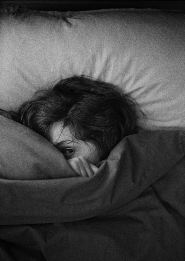 woman peeking through sheets on bed