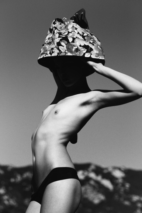 topless woman wearing hat, face obscured by shadow