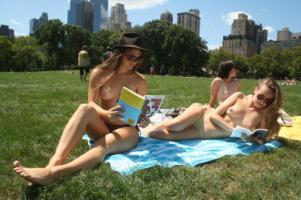 topless women in hats reading books in central park.